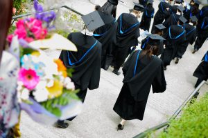 Graduating students wearing grad caps and walking away from the camera